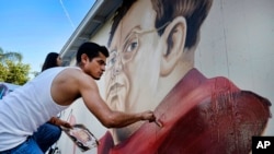 FILE - Muralist Levi Ponce paints a portrait of Mexican artist Diego Rivera in the Pacoima section of Los Angeles, June 6, 2015. 