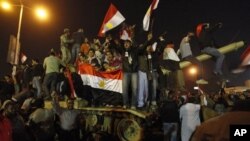 Egyptian citizens stand on an Egyptian military tank as they celebrate after President Hosni Mubarak resigned and handed power to the military at Tahrir Square in Cairo, Egypt, February 11, 2011