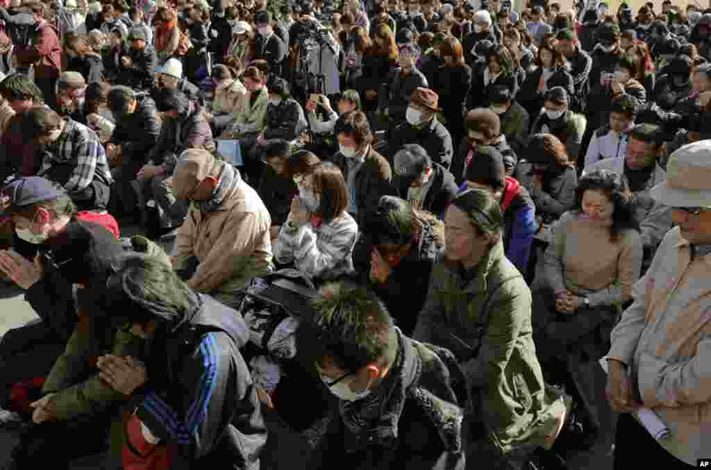 People observe a moment of silence for the victims of the March 11, 2011 earthquake and tsunami during an event at a park in Tokyo, March 11, 2013. 