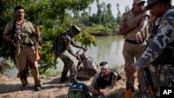 An Indian army soldier, second left, gives first aid to paramilitary soldiers who were injured in a highway ambush in Pampore, on the outskirts of Srinagar, Indian-controlled Kashmir, June 25, 2016.