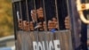 FILE - Student protesters are seen gripping the bars of a prison vehicle as they are transported to a court in Letpadan, March 11, 2015. Myanmar's opposition National League for Democracy (NLD) demanded an inquiry into clashes between police and protesters. 