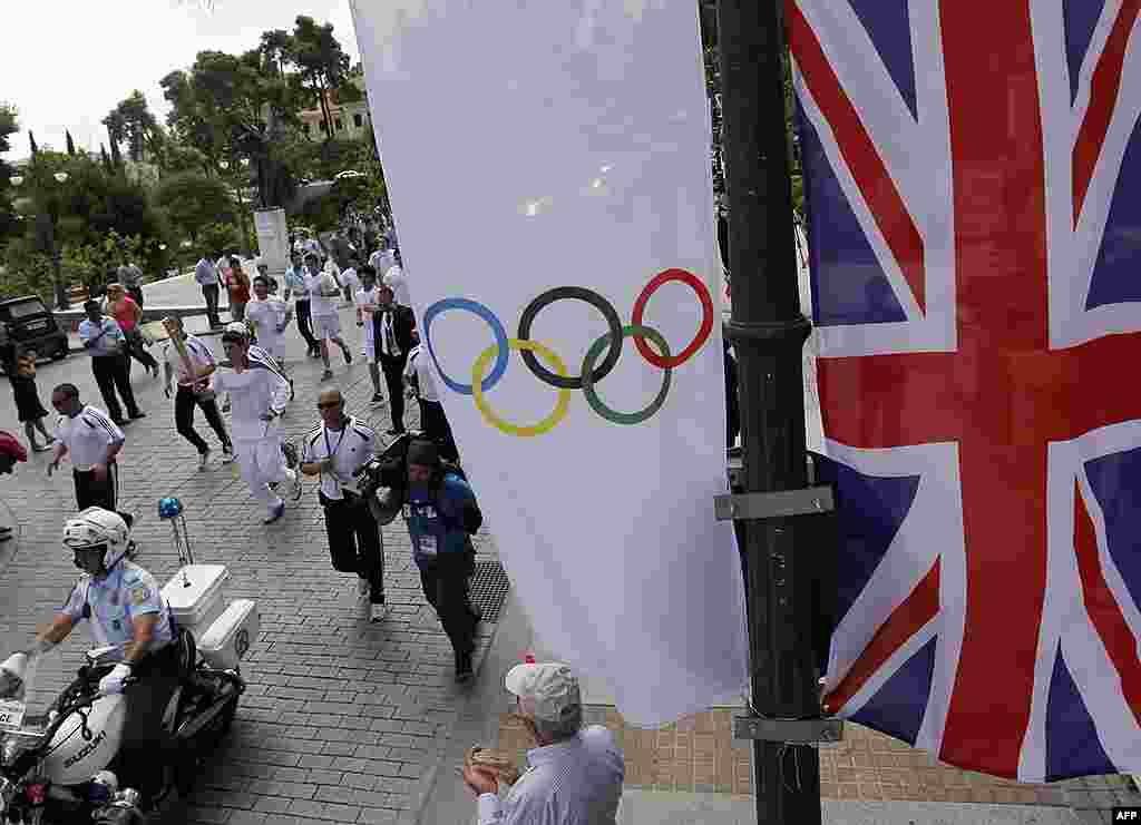 A Union flag and an Olympic flag are seen as Chris Theodoropoulos, a Greek student who plays basketball for a local team, runs with the Olympic flame. (Reuters)