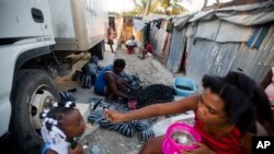 FILE - Adrienne St. Fume, at center, bags charcoal in the Delmas tent camp in Port-au-Prince, Haiti, Dec. 5, 2016. The camp aids people displaced by the 2010 earthquake. The U.S. government is reviewing Temporary Protected Status for Haitians who sought refuge in the United States after the quake.