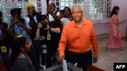 Le Premier ministre de l'île Maurice et candidat du Mouvement socialiste militant (MSM), Pravind Jugnauth (au centre), dépose son bulletin de vote dans l’urne d'un bureau de vote à Port-Louis, le 10 novembre 2024. (Photo de Rishi ETWAROO / L'Express Maurice/AFP)