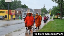 A group of local Laotian and Buddhist monks from Wat Lao Samakky Temple walk with Phra Sutham Nateetong, the Thai monk who is walking for peace across America, Fort Wayne, Indiana June 9, 2019.