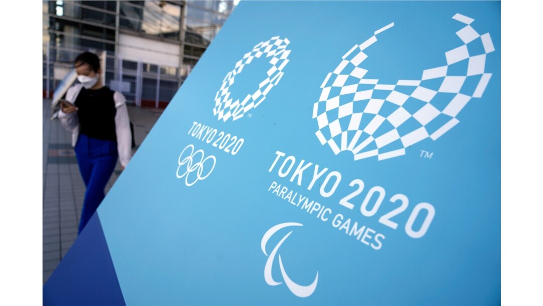 A woman walks near a sing of the Tokyo 2020 Olympic and Paralympic Games, Aug. 20, 2021, in Tokyo. The Tokyo Paralympics open on Aug. 24 in a ceremony at Tokyo's National Stadium.