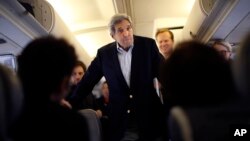 Menteri Luar Negeri AS John Kerry berbicara dengan wartawan di pesawat sebelum pergi ke Wina, Austria, di pangkalan udara Andrews di Maryland (26/6). 