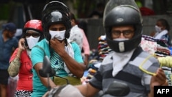 Motorists wearing facemasks as a preventive measure against the spread of the Covid-19 coronavirus, ride through a market in New Delhi on August 30, 2020. - India on August 30 set a coronavirus record when it reported 78,761 new infections in 24…