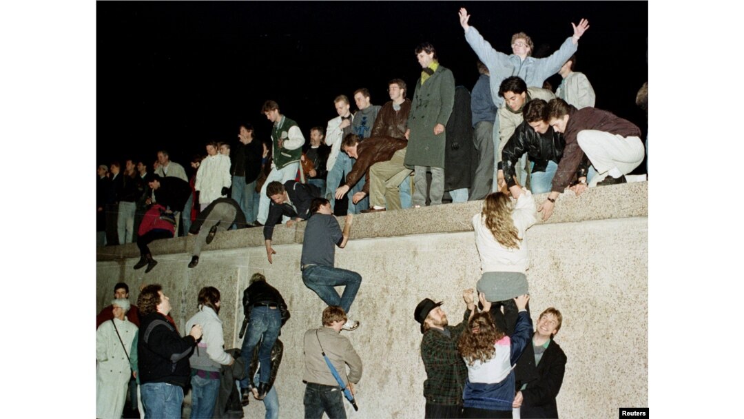 FILE - East German citizens climb the Berlin wall at the Brandenburg Gate as they celebrate the opening of the East German border in 1989.