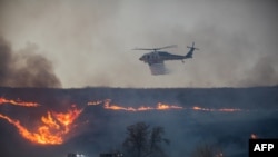 A firefighting helicopter drops water over the Hughes Fire in Castaic, a northwestern neighborhood of Los Angeles County, California, Jan. 22, 2025.