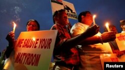 People hold candles and placards during a vigil for the soldiers who were killed after gunmen attacked an Indian army base in Kashmir's Uri, Mumbai, India, Sept. 19, 2016.