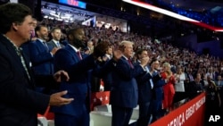 Republican presidential candidate former President Donald Trump and Republican vice presidential candidate Senator JD Vance, attend the first day of the Republican National Convention, July 15, 2024, in Milwaukee. At left is Tucker Carlson and Representative Byron Donalds.