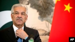 Pakistan's Foreign Minister Khawaja Muhammad Asif adjusts his necktie during a joint press conference at the Diaoyutai State Guesthouse in Beijing, Sept. 8, 2017.