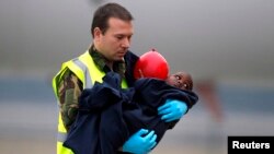 Seorang anggota Angkatan Udara Kerajaan Belanda menggendong seorang anak turun dari pesawat bantuan Belanda yang tiba dari Port-au-Prince, Haiti, di bandara Eindhoven, Belanda, 21 Januari 2010. (Foto: dok).