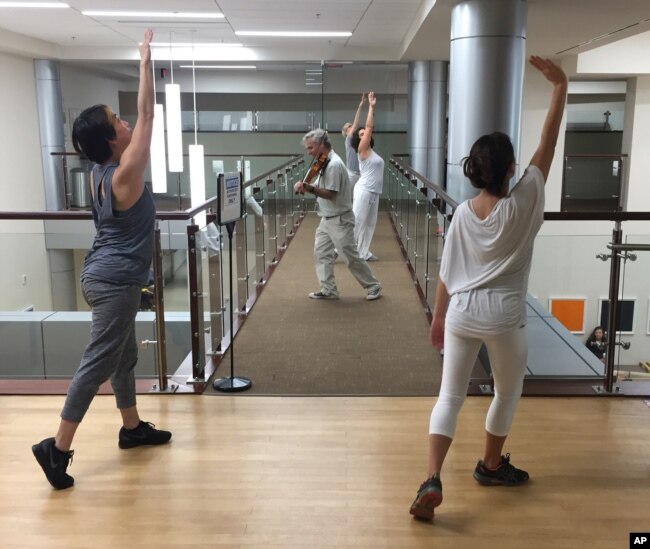 FILE - Violinist Anthony Hyatt leads dancers through MedStar Georgetown University Hospital in Washington, Oct. 11, 2017.