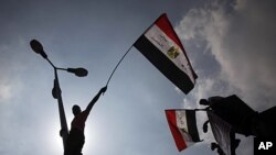 Egyptian protesters wave from lamp posts hanging their national flags at Tahrir Square, the focal point of the Egyptian uprising, in Cairo, September 9, 2011.