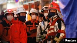 Petugas pemadam kebakaran berdiri di luar gedung tempat kebakaran terjadi di Osaka, Jepang, 17 Desember 2021. (Foto: REUTERS/Kim Kyung-Hoon)