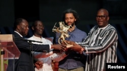 The French-Senegalese Alain Gomis (2nd R), director of the movie "Felicite," receives the Etalon d’Or de Yennenga from Burkina Faso's President Roch Marc Christian Kabore (R) and Ivory Coast's president Alassane Ouattara (L) during the FESPACO film festival, March 4, 2017.