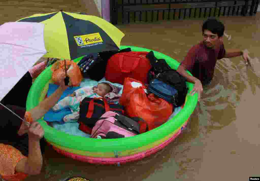 A baby is evacuated in an inflatable boat by a rescue team after floods hit a residential area in Tangerang, near Jakarta, Indonesia, Jan. 1, 2020, in this photo taken by Antara Foto.