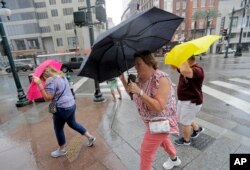 Martha Young, en el centro, Patricia Plishka, a la izquierda, y su esposo Glen, a la derecha, luchan contra el viento y la lluvia del huracán Barry a medida que se acerca el aterrizaje del sábado, 13 de julio de 2019, en Nueva Orleans. (Foto AP / David J. Phillip)