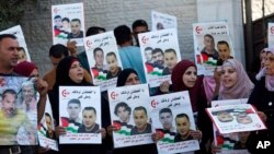FILE - Palestinian demonstrators hold pictures of detainees as they take part in a protest in solidarity with Palestinian prisoners held in Israeli jails, in front of the United Nations headquarters in the West Bank city of Ramallah.