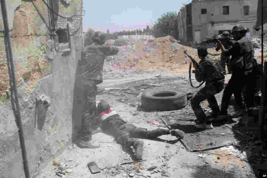 Syrian army personnel shoot towards rebel fighters during a tour for journalists organized by the Syrian Information Ministry in the Damascus suburb of Jobar, July 14, 2013. 