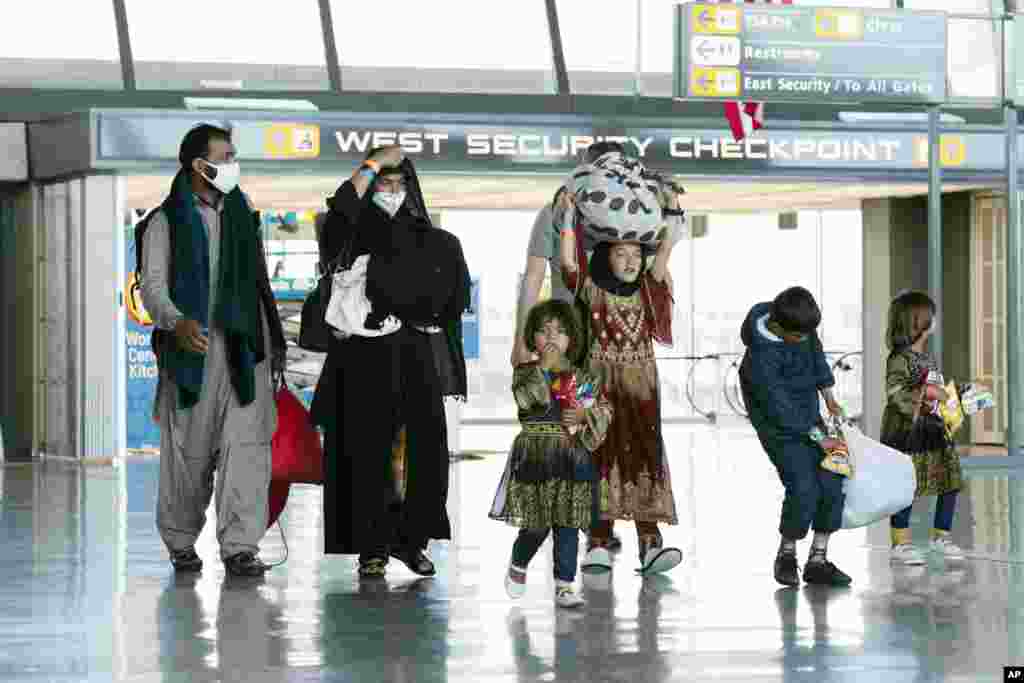 Families evacuated from Kabul, Afghanistan, walk through the terminal before boarding a bus after they arrived at Washington Dulles International Airport, in Chantilly, Virginia.