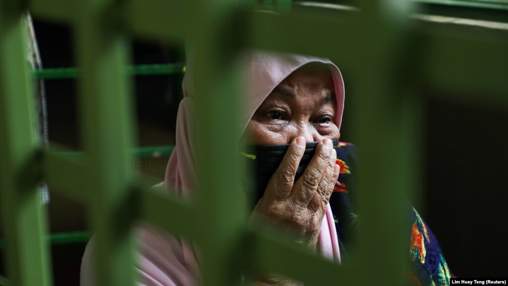 Halijah Naemat, 74, cries while members of public come over to help after she hung a white flag outside her home during an enhanced lockdown, amid the coronavirus disease (COVID-19) outbreak, in Petaling Jaya, Malaysia July 6, 2021. (REUTERS/Lim Huey Teng)