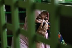 Halijah Naemat, 74, menangis ketika anggota masyarakat datang untuk membantu setelah dia mengibarkan bendera putih di luar rumahnya selama lockdown, di tengah wabah COVID-19, di Petaling Jaya, Malaysia 6 Juli 2021. (Foto: REUTERS/ Lim Huey Teng)