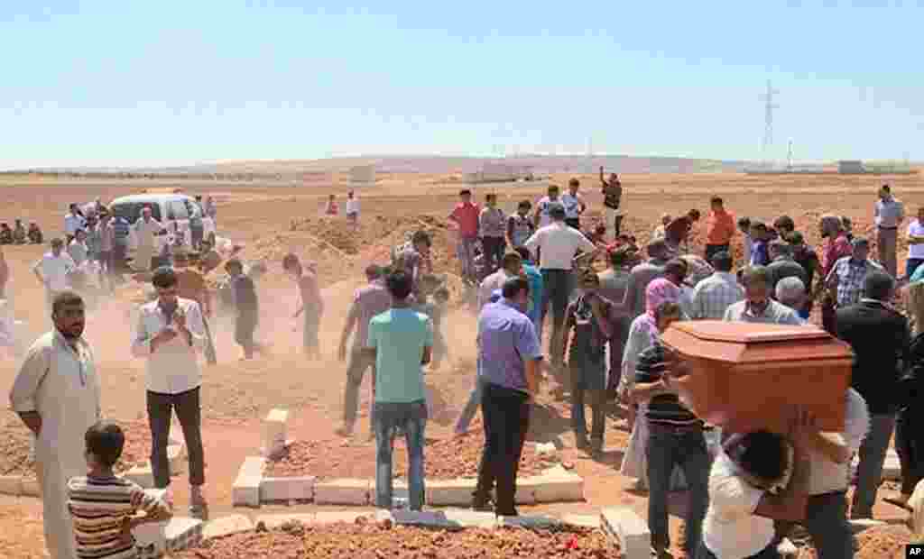 In this image made from video, mourners carry a coffin during the burial of Rehan Kurdi and her sons Aylan, 3, and Galip, 5, after they drowned during a desperate voyage from Turkey to Greece, in their hometown of Kobani, the Syrian Kurdish region they fl