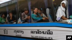 FILE PHOTO - Cambodian migrant workers sit in a bus upon arrival at Cambodia-Thailand's international border gate in Poipet, Cambodia, from Thailand, Tuesday, June 17, 2014.