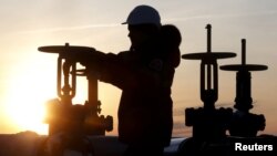 FILE - A worker checks the valve of an oil pipe at the Lukoil owned Imilorskoye oil field near Kogalym, Russia, Jan. 25, 2016.