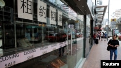 A woman walks past a shop with a closing sale in Hong Kong, China, Oct. 29, 2019. 