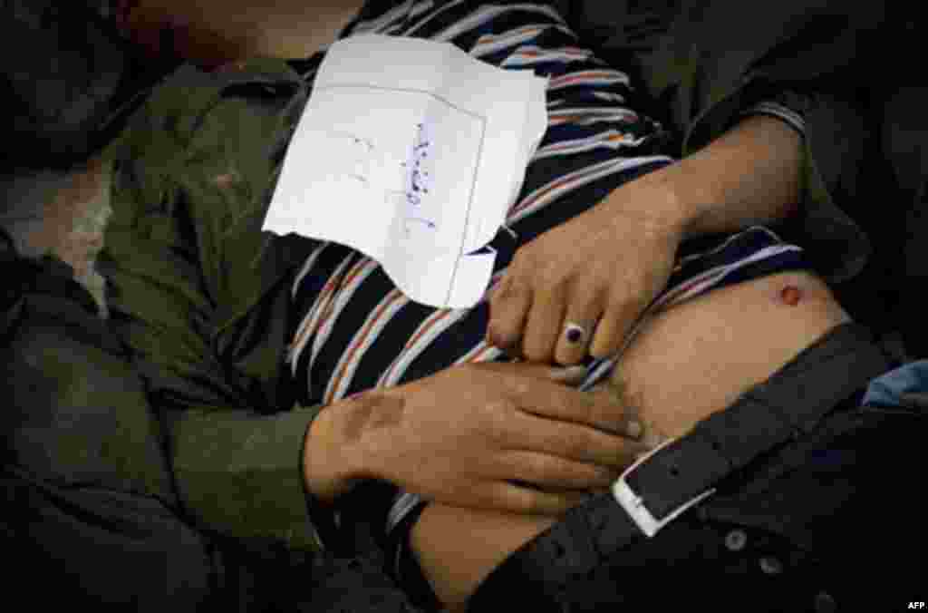 A note is attached to a dead body of a soldier loyal to Libyan leader Moammar Gadhafi in the morgue of the Jalaa hospital in Benghazi, eastern Libya, Saturday, March 19, 2011. In the hours before the no-fly zone over Libya went into effect, Gadhafi sent w