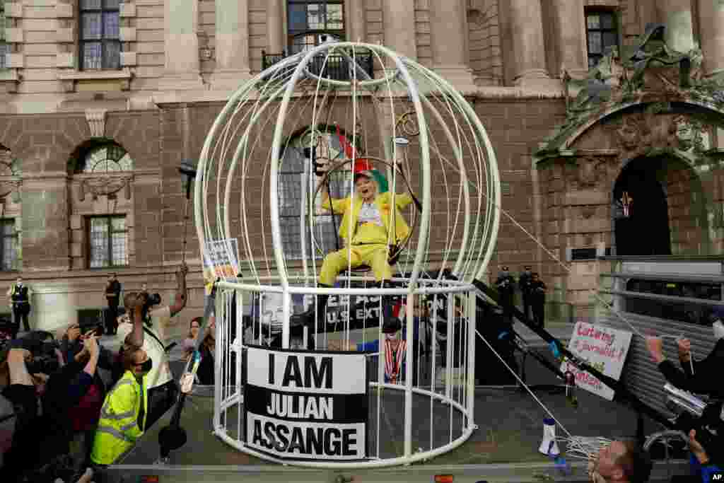 Fashion designer Vivienne Westwood sits suspended in a giant bird cage outside the Old Bailey court, in London, in protest against the extradition of WikiLeaks founder Julian Assange to the U.S.