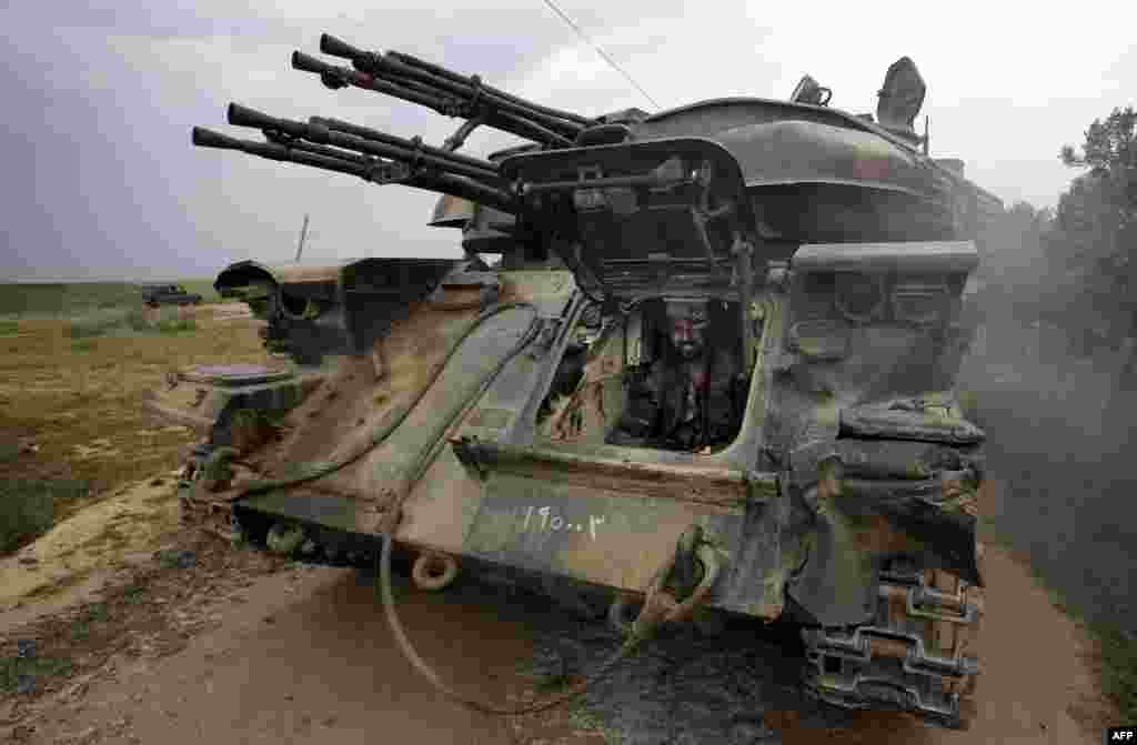 A Syrian soldier sits inside a tank as troops take control of the village of Western Dumayna, some seven kilometers north of the rebel-held city of Qusayr.