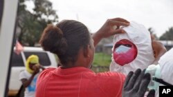 Petugas kesehatan mengenakan pakaian pelindung sebelum memindahkan jenazah pasien Ebola yang tewas di Monrovia, Liberia (12/8).