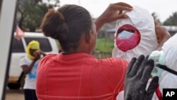 Un travailleur sanitaire aidant un collègue avec son équipement de protection pour recueillir le corps d'un homme soupçonné d'avoir succombé au virus d’Ebola à Monrovia, au Libéria, le 12 août 2014.