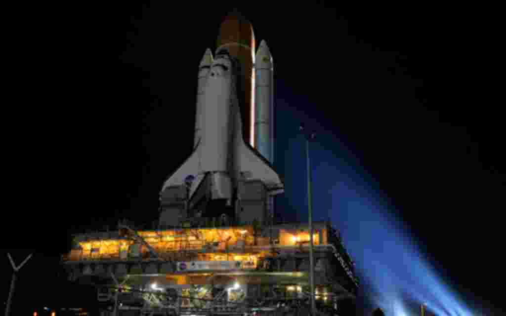 En medio de luces de xenón brillante, el transbordador Discovery hace su caminata nocturna, conocida como "lanzamiento" al Edificio de Ensamblaje de Vehículos a plataforma de lanzamiento de la NASA.