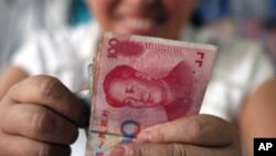 FILE - A bookstore vendor counts Chinese renminbi notes in Chengdu, in southwest China's Sichuan province.