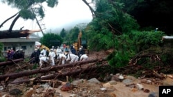 In this photo provided by Nagasaki Kenou Wide Area Fire Department, rescuers work at a mudslide site following heavy rain in Obama, Unzen city, Nagasaki prefecture, Japan, Aug. 14, 2021.