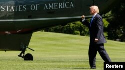 U.S. President Donald Trump pumps his fist at his aides and staff members looking on as he departs to spend the weekend at his New Jersey golf estate from the South Lawn of the White House in Washington, June 9, 2017. 