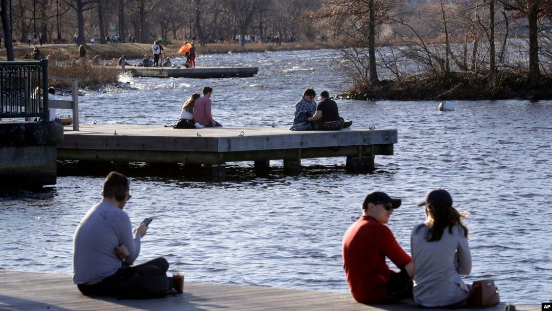 Para pengunjung taman Charles River Esplanade di Boston duduk-duduk menikmati cuaca hangat yang tak biasanya, 12 Januari 2020. (Foto: AP)