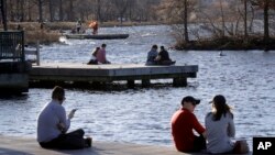 Para pengunjung taman Charles River Esplanade di Boston duduk-duduk menikmati cuaca hangat yang tak biasanya, 12 Januari 2020. (Foto: AP)