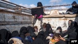 Women and children fleeing from the last Islamic State group's tiny pocket in Syria sit in the back of a truck near Baghuz, eastern Syria, Feb. 11, 2019. 