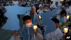 Građani drže sveće i kartone u obliku mape Korejskog poluostrva tokom dnevnog bdenja za uspeh samita Tramp - Kim, u blizini ambasade SAD u Selu, Južna Koreja, 9. juna 2018.
