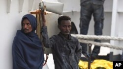 Migrants stand aboard the Italian Coast Guard ship Diciotti, moored at the Catania harbor, Aug. 21, 2018. 