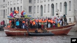 Amnesty International activists protest against the ongoing migrant crisis with a boat filled with mannequins wearing life vests outside the Maritime Museum, rear, during an informal meeting of EU Justice and Home Affairs ministers at the Maritime Museum 