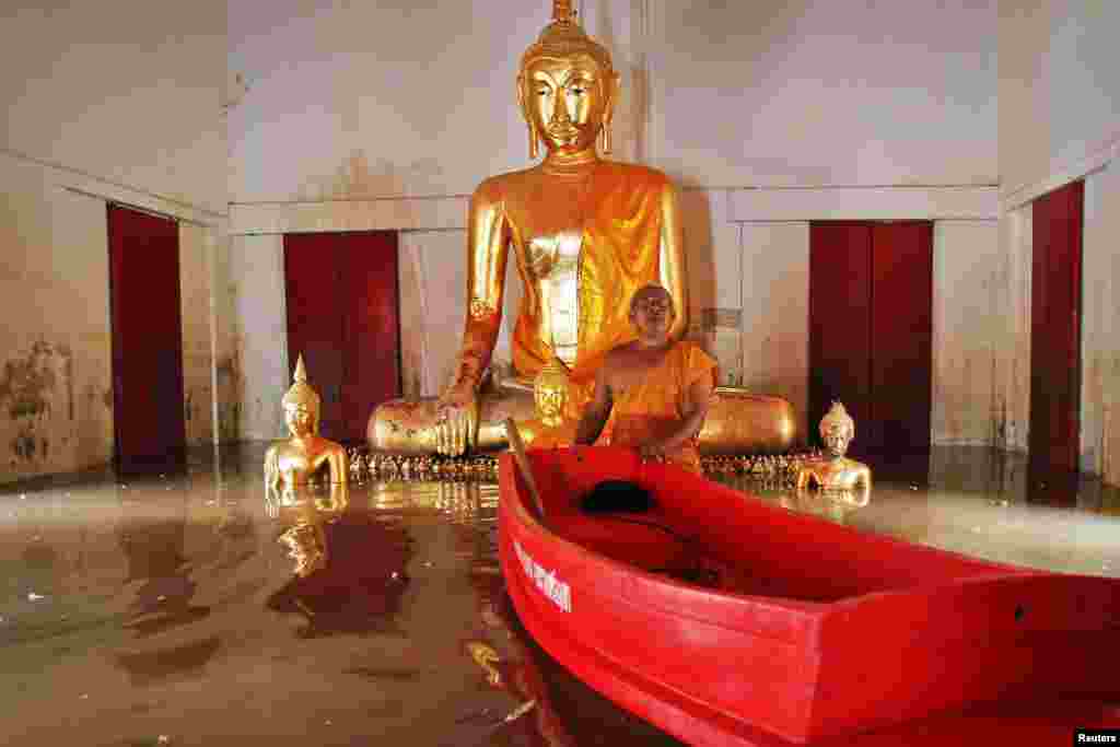 Một nhà sư đẩy chiếc thuyền plastic nhỏ trong khi chỉ cho các thông tín viên thấy ngôi chùa  của ông đang bị ngập lụt tại quận Ban Ban, tỉnh Ayutthaya hôm 2-10-2013, ở Thái Lan.