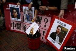 FILE - A pro-democracy activist burns a letter next to pictures of missing staff members of a publishing house and bookstore outside the Chinese liaison office in Hong Kong, Jan. 3, 2016.